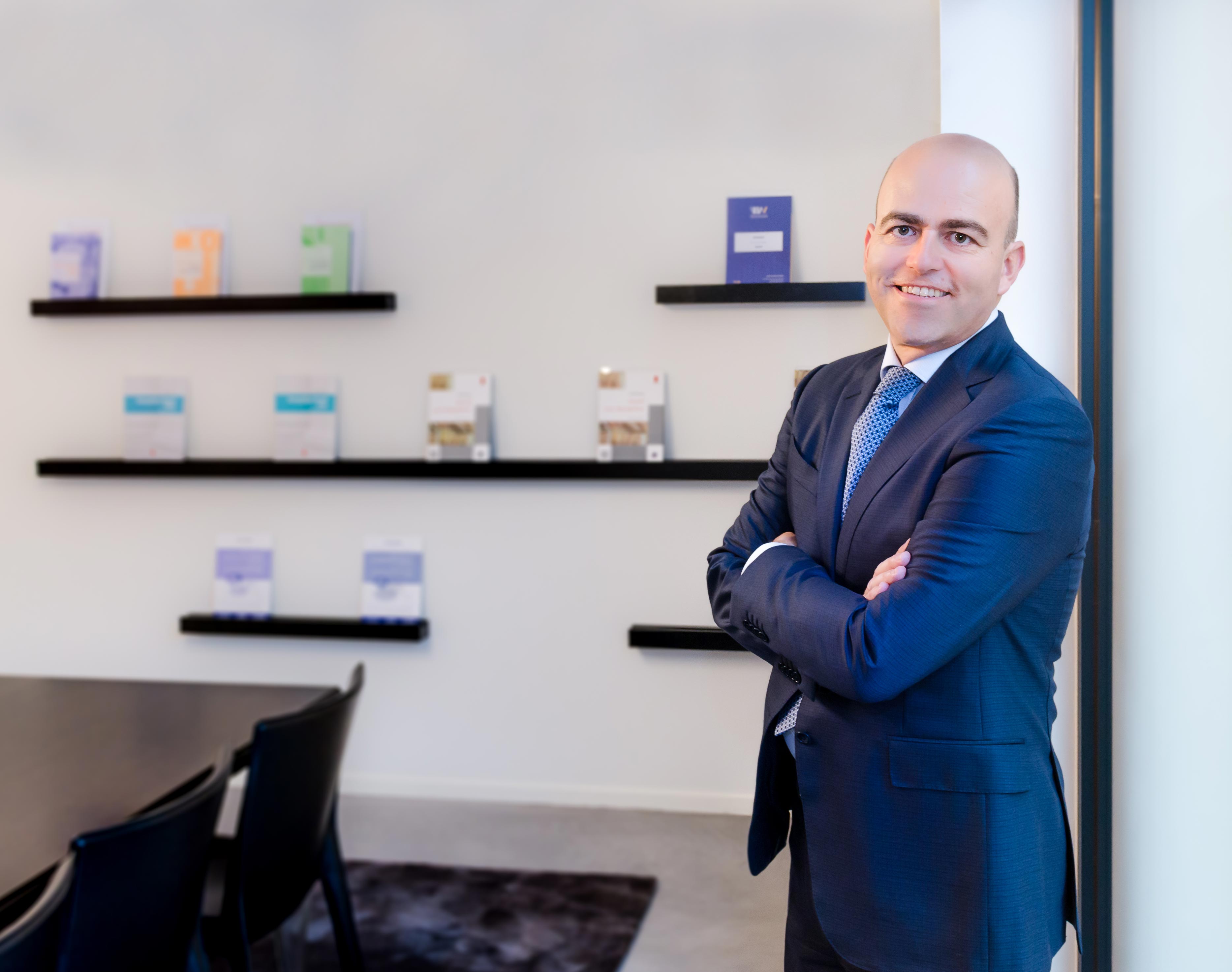 Thierry Lauwers, oprichter van Lauwers Tax Lawyers, in een donkerblauw maatpak staand in zijn kantoor met fiscale publicaties op de achtergrond
